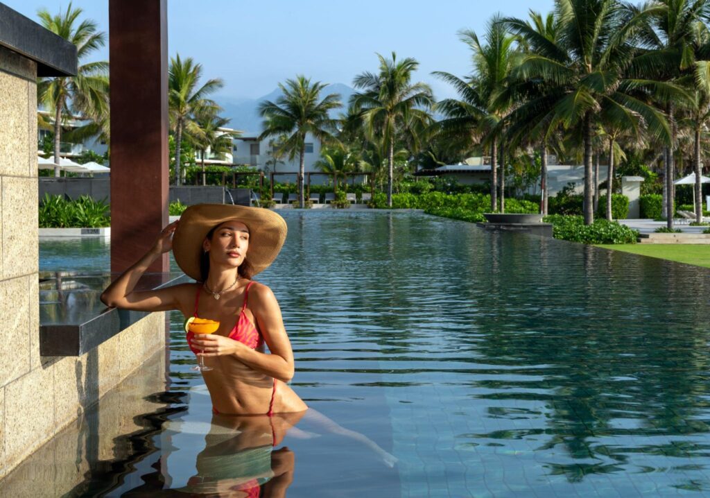 Guests enjoying a sunset stroll along the shoreline beside a luxury property, reflecting the atmosphere of beach resorts in Cam Ranh.